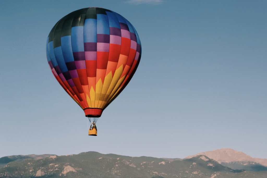 A colorful hot air balloon in the sky with Colorado landscape below